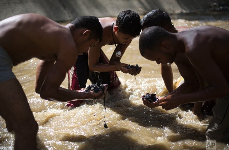 People dive in Venezuela’s most polluted river for scrap metal to survive